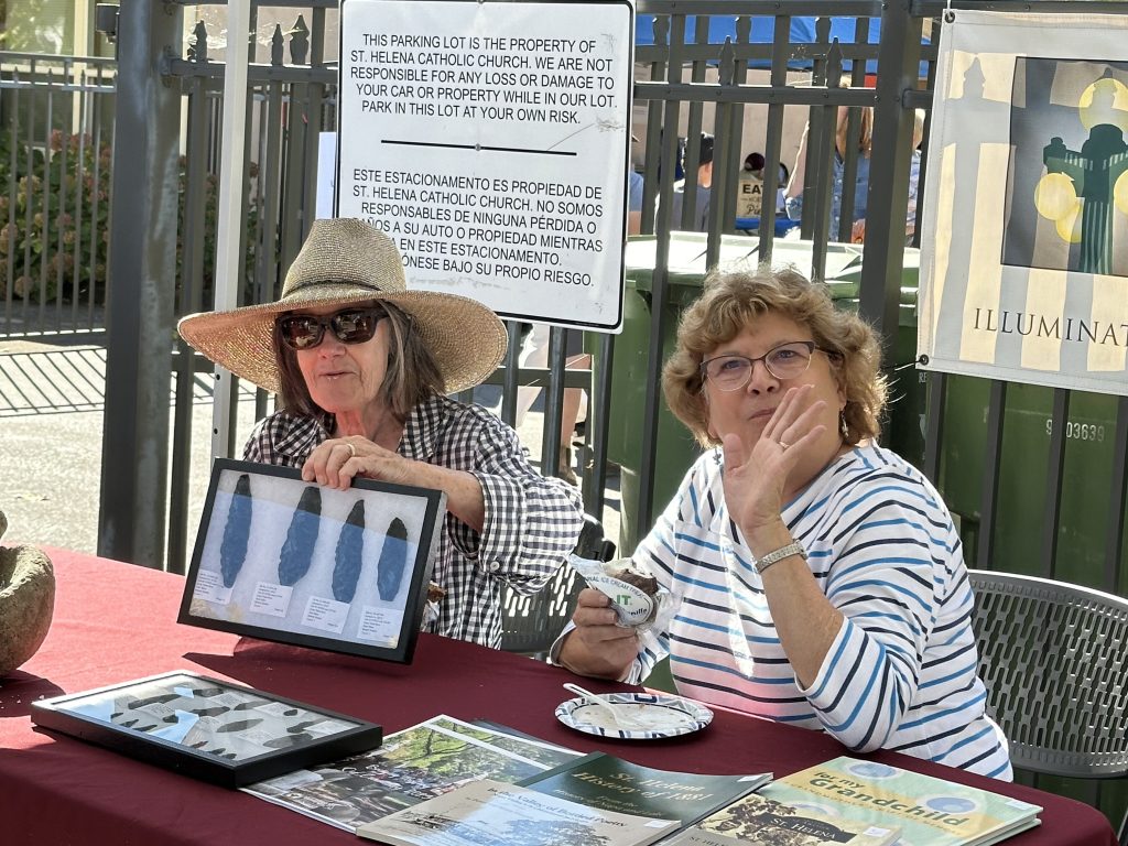 Two St. Helena Historical Society volunteers at the Harvest Festival booth with a display of arrowheads