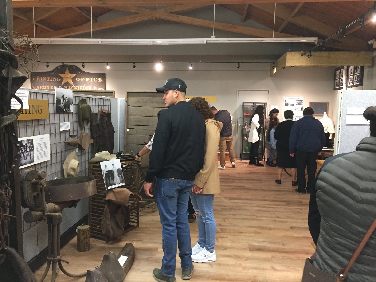 Museum visitors viewing the ranching exhibit below the antique Star printing-office sign.