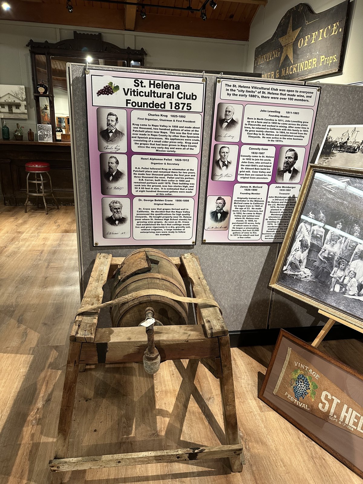Antique wooden basket wine press before a panel on the St. Helena Viticultural Club, founded 1875.
