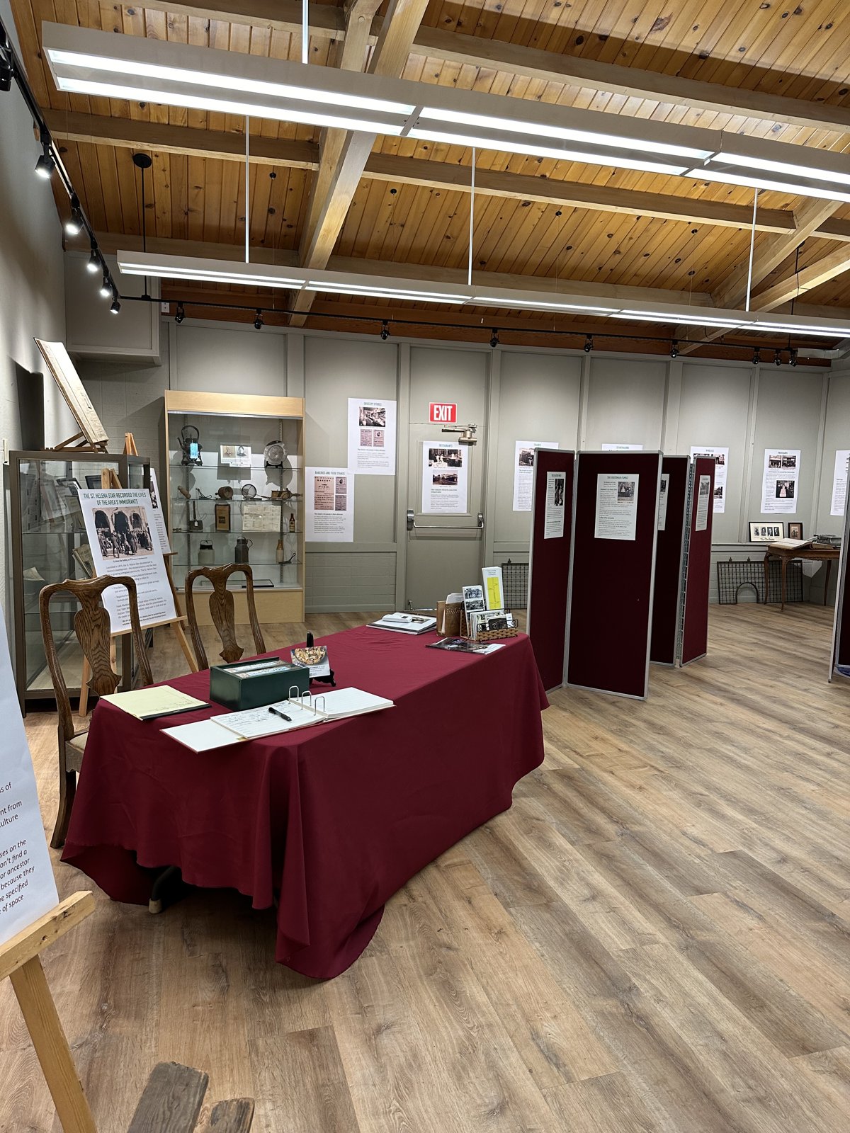 The Heritage Center’s rotating exhibit room with display cases, panels and a red-draped table.